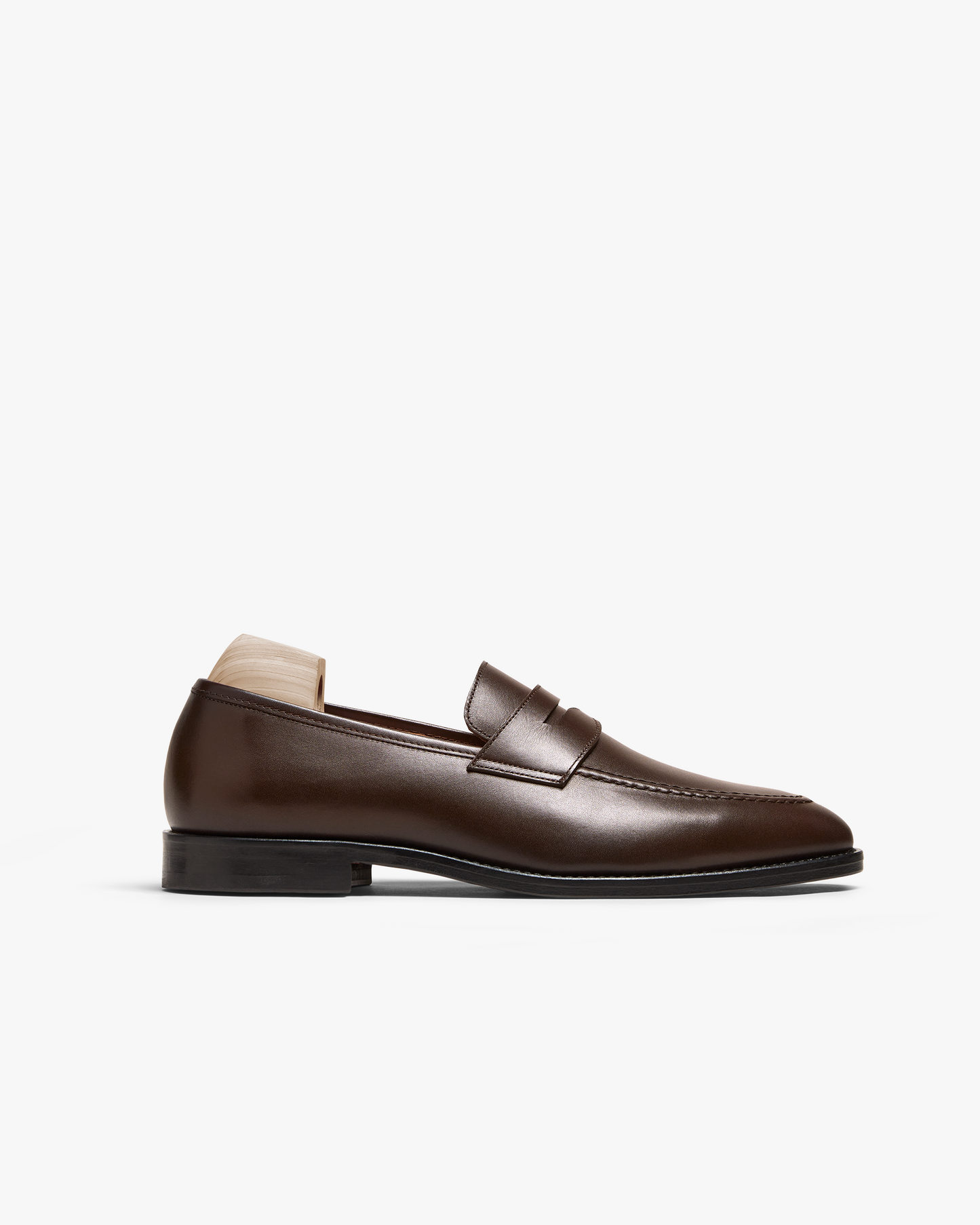 Smögen loafer in dark brown calf leather features a gently rounded toe, classic penny strap, and hand-finished seams, shown in a side profile against a white background. The smooth, full-grain upper and black sole highlight its refined, versatile design suitable for both formal and casual men's outfits.