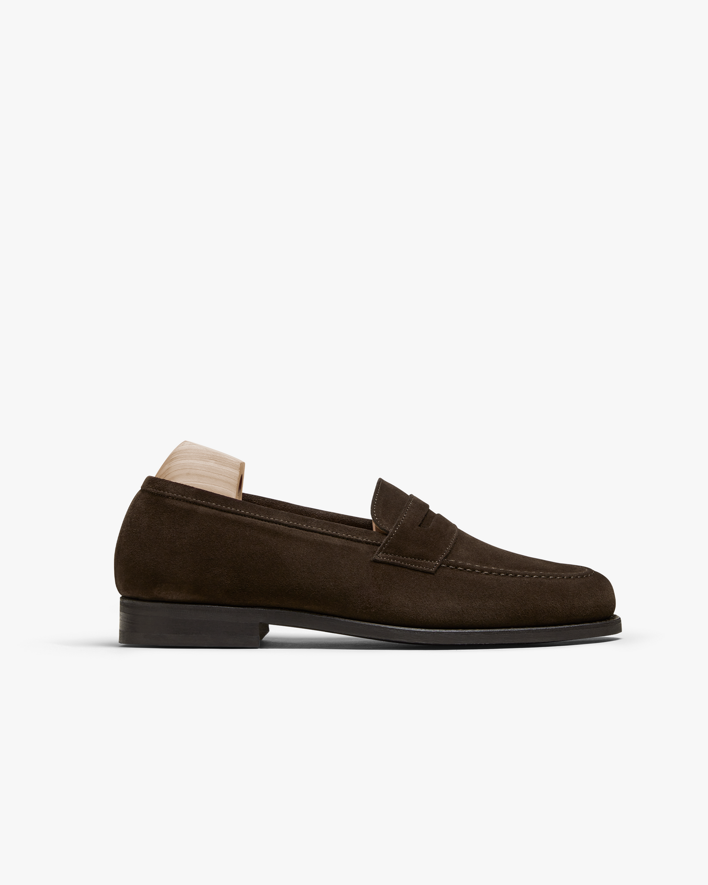 Stenhammar II in dark brown suede features a softly rounded silhouette with an apron front, subtle stitching, and a rich suede texture, shown in profile with a wooden shoe tree inserted.