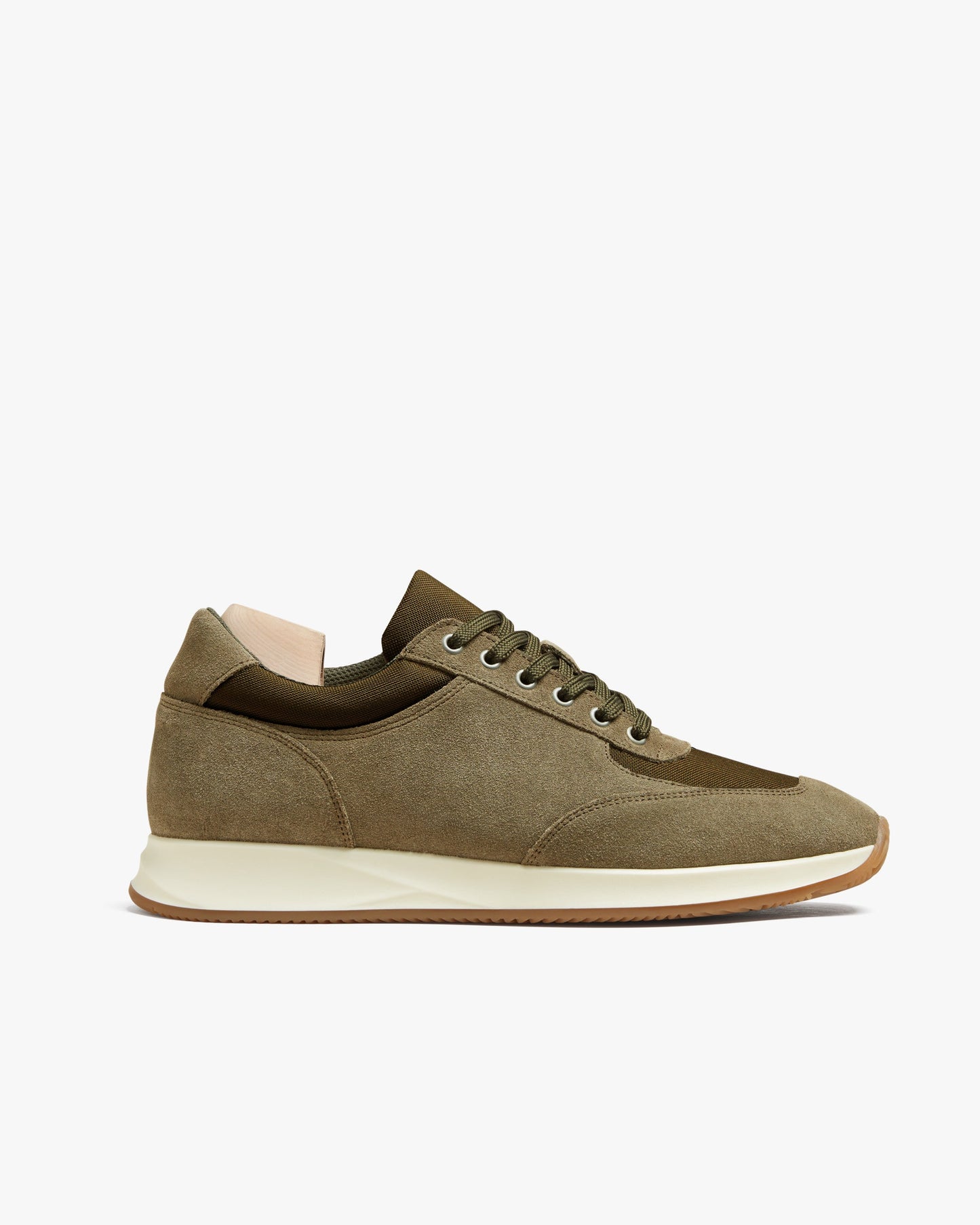 Stensund in moss green suede features a softly rounded toe, tonal mesh panels, and a contrast off-white sole with a gum outsole, blending athletic inspiration with refined Scandinavian style. The lace-up sneaker is shown in a side profile, highlighting its harmonious mix of textures and versatile design.