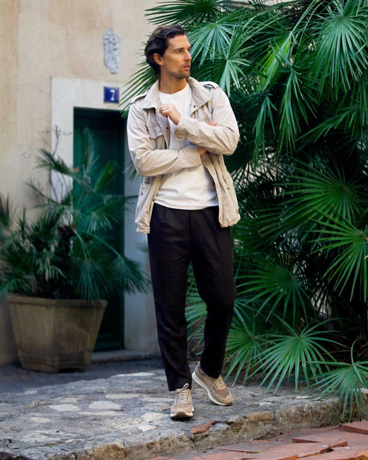 A man walks outdoors in Stensund in sand suede, paired with brown slacks, a white shirt, and a light jacket, showcasing the trainer's soft beige suede and versatile style for both business casual and relaxed settings.
