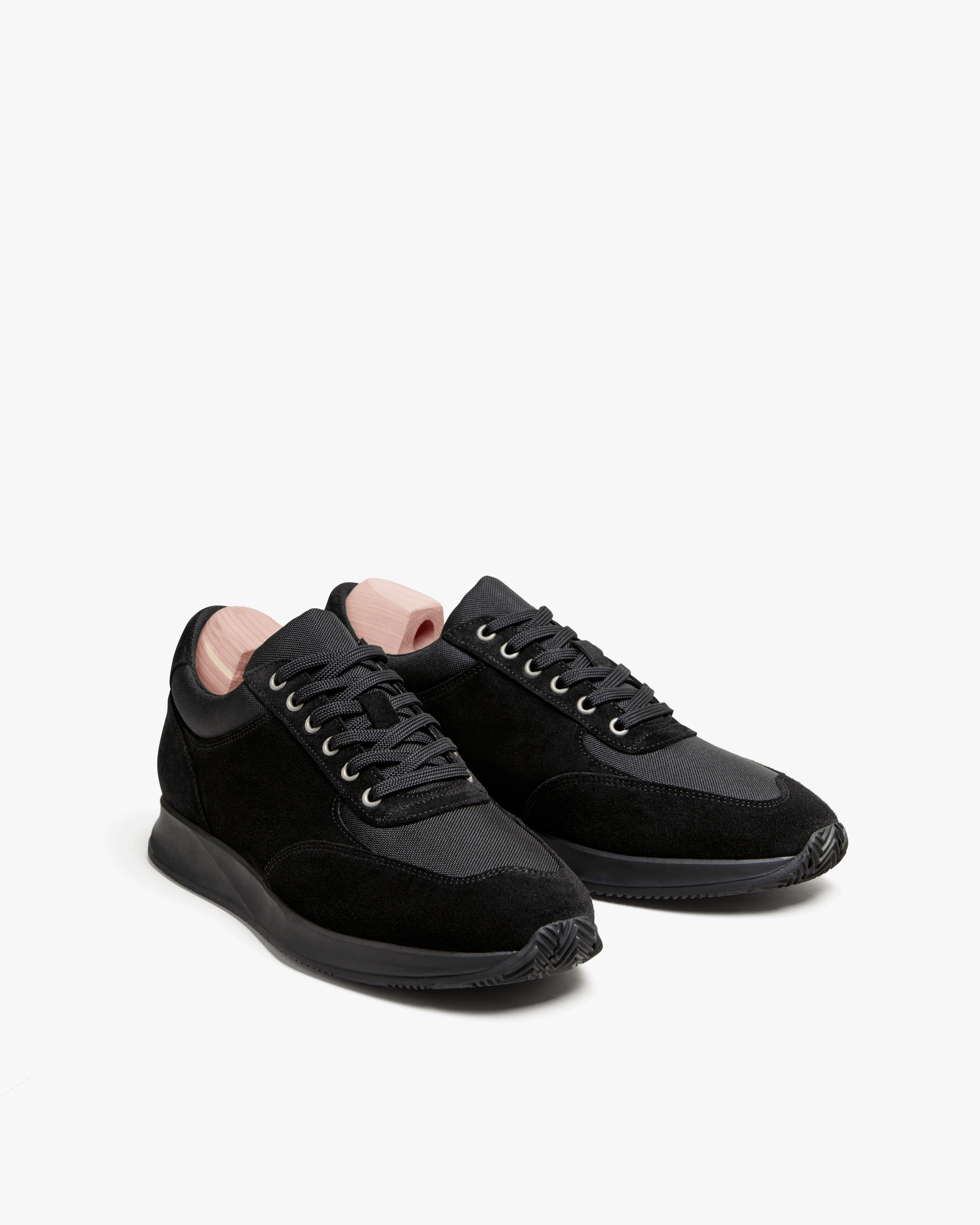 Stensund in black suede displayed at an angle, featuring soft suede and tonal mesh panels, lace-up closure, and a streamlined black rubber sole for a refined yet sporty look.