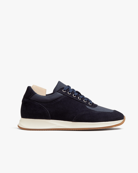 Stensund in navy suede features a sleek, low-profile silhouette with deep navy suede and tonal mesh panels, set on a natural-toned rubber sole with a gum outsole for a refined, athletic look. The lace-up trainer is shown in a side view, highlighting its softly contoured lines and versatile styling.