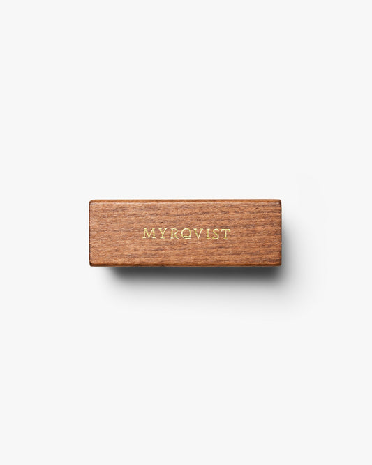 A top-down view of the Suede Brush – Brass, showing the wooden handle with the Myrqvist logo in gold lettering.