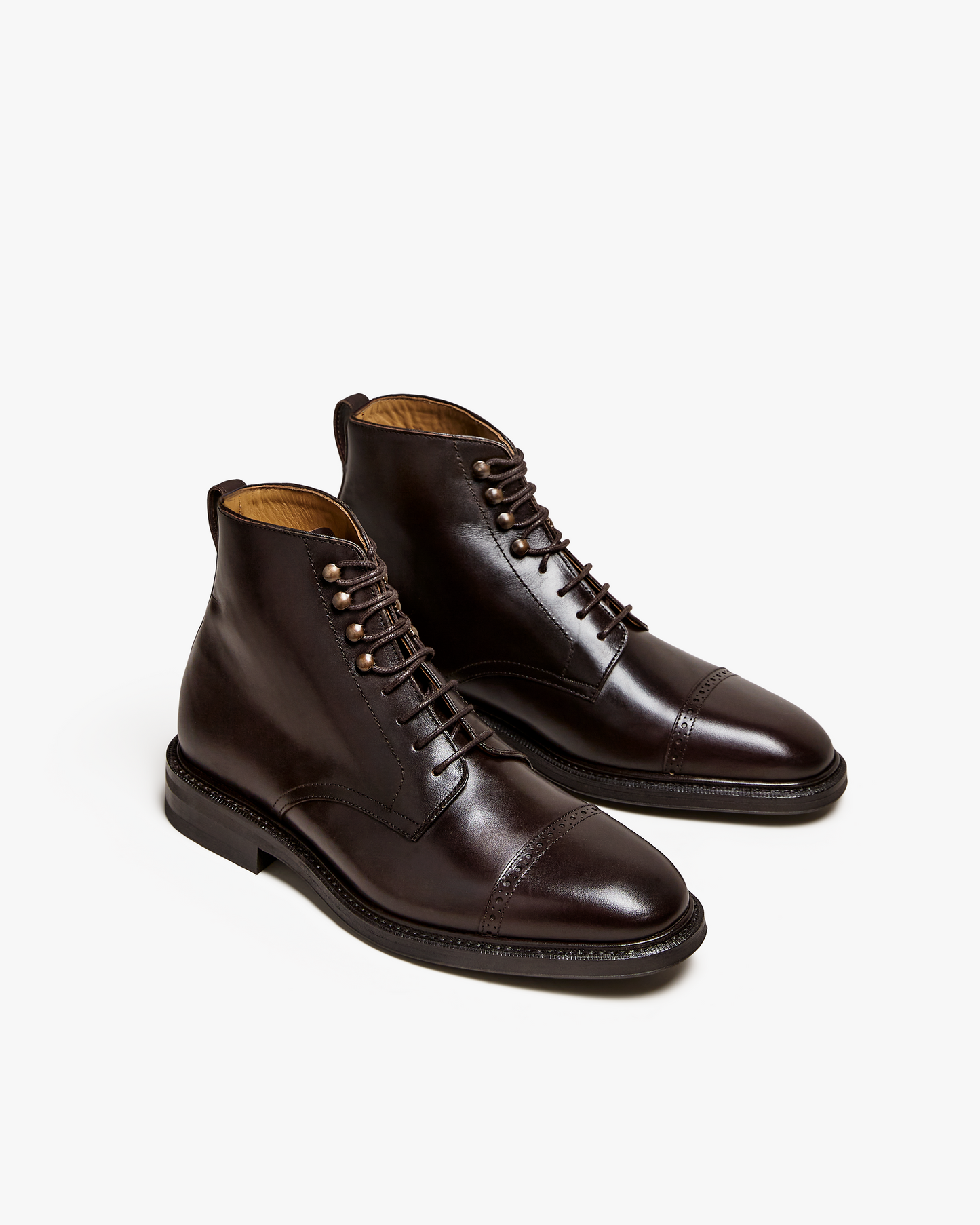 Tjärnö II in dark brown calf displayed at an angle, featuring smooth full grain leather, cap toe with subtle broguing, metal lace hooks, and a rounded silhouette for a refined and versatile men's boot.