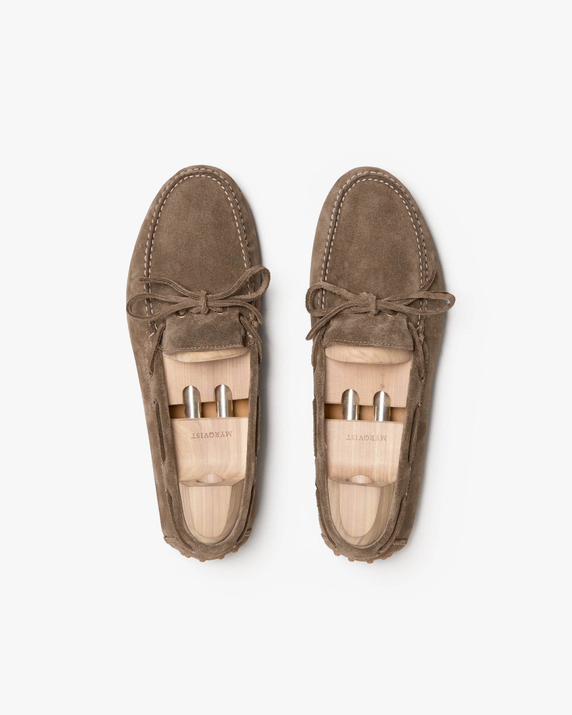 Tofta loafers in taupe suede shown from above, highlighting the soft suede upper, tonal stitching, and bow detail, with wooden shoe trees maintaining their shape.
