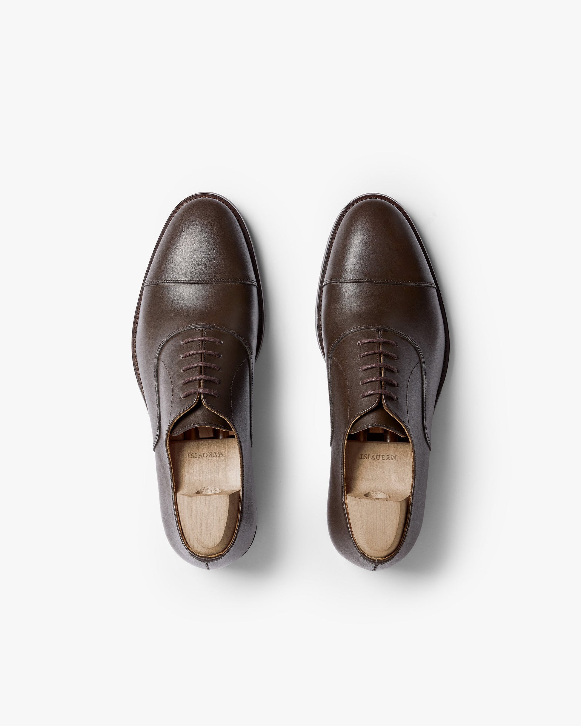 Vinterviken II in dark brown calf, a pair of classic oxford shoes with chiseled cap toes and clean stitching, shown from above with wooden shoe trees inserted.
