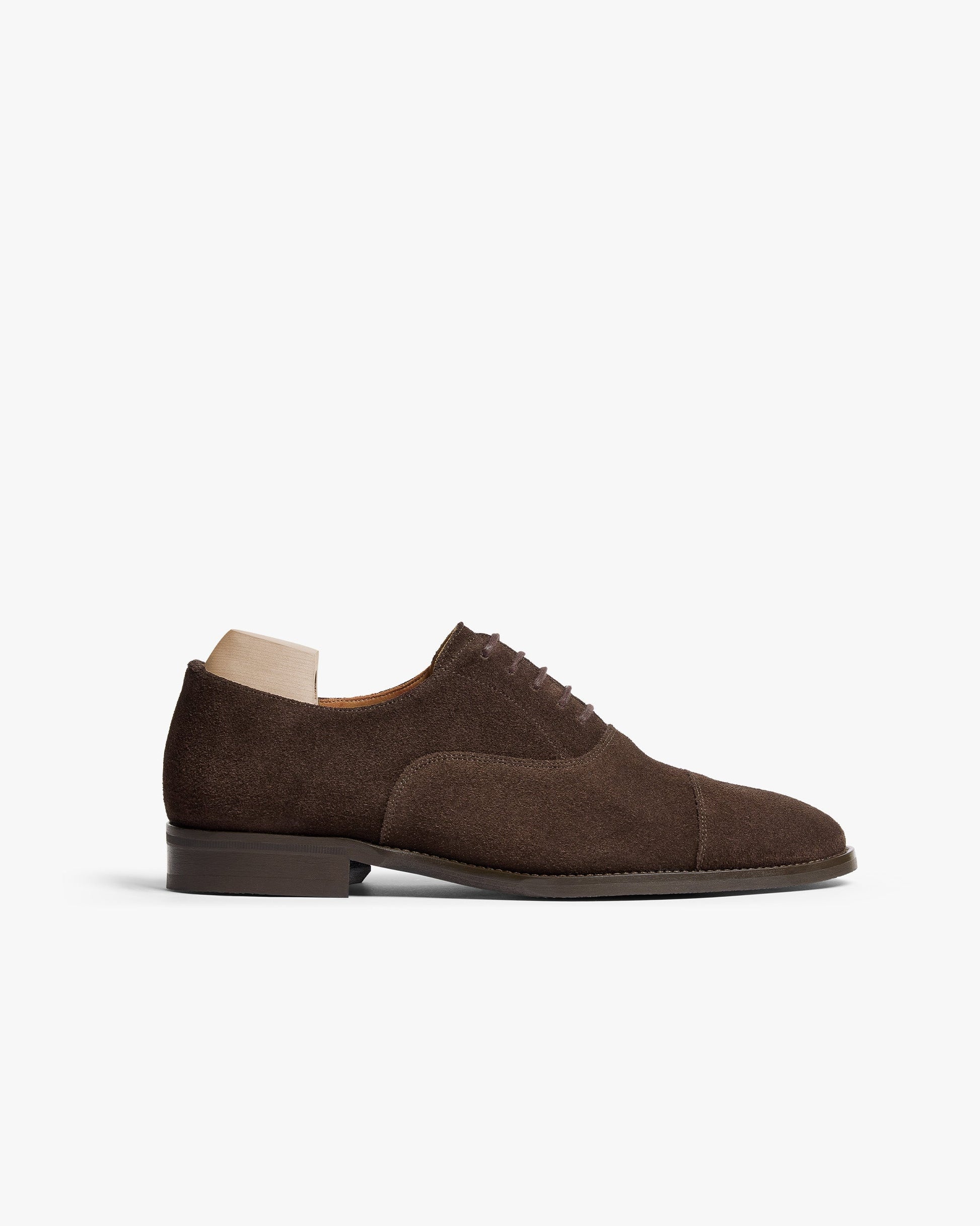 Vinterviken II in dark brown suede features a classic oxford silhouette with a gently chiseled cap toe, fine stitching, and a smooth, understated finish, shown with a wooden shoe tree inside.