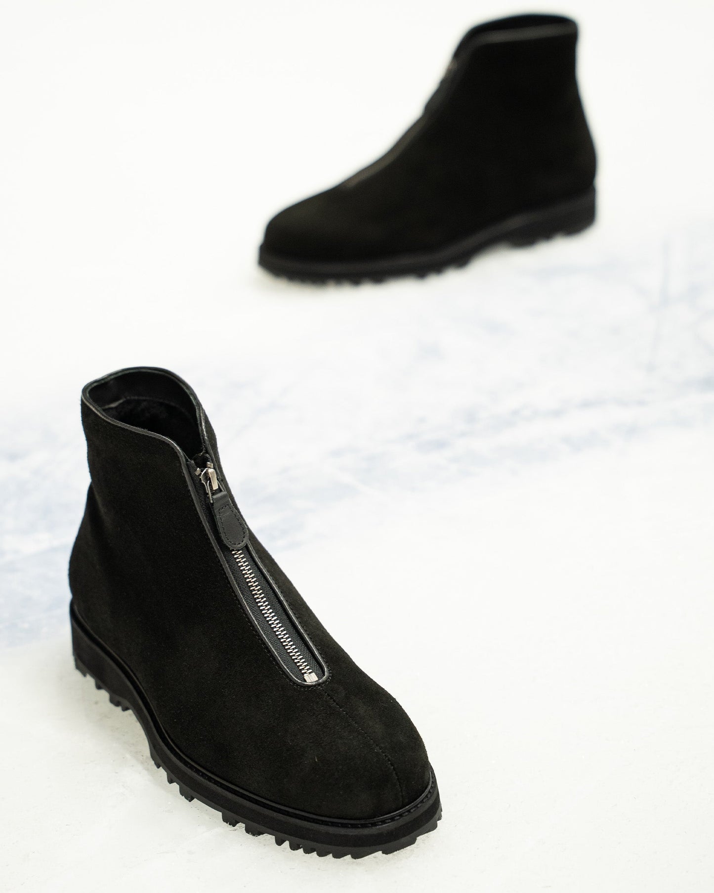Funäs in black suede displayed on a light surface, featuring a minimalist silhouette with a central zipper and rugged Explorer sole, designed for versatile winter wear.