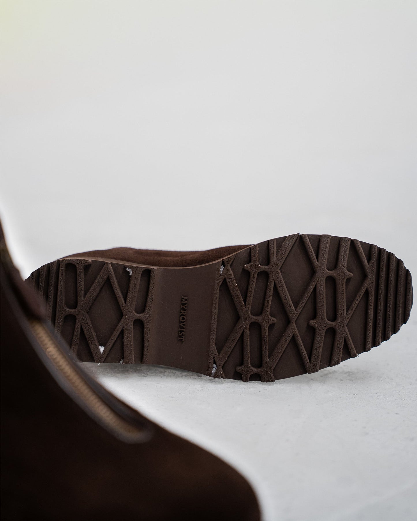 Close-up of the Explorer sole on Funäs in dark brown suede, highlighting the rugged tread pattern designed for grip and stability in winter conditions. The boot’s central zipper and soft suede finish are partially visible, emphasizing both function and refined style.