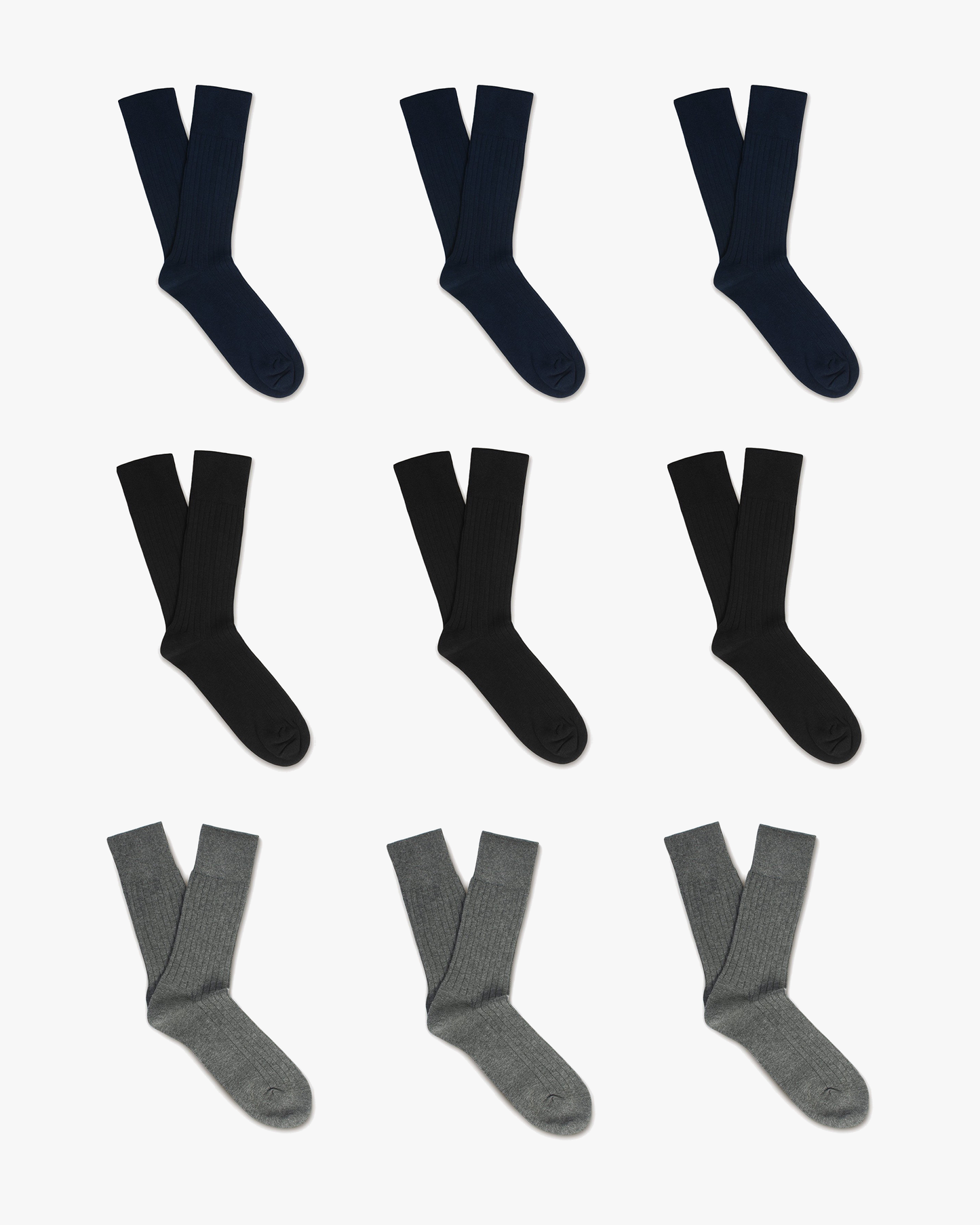 Nine pairs of Oscar ribbed cotton socks in navy, black, and grey are neatly arranged in three rows, showcasing the classic crew length and subtle ribbed texture of each color variation.