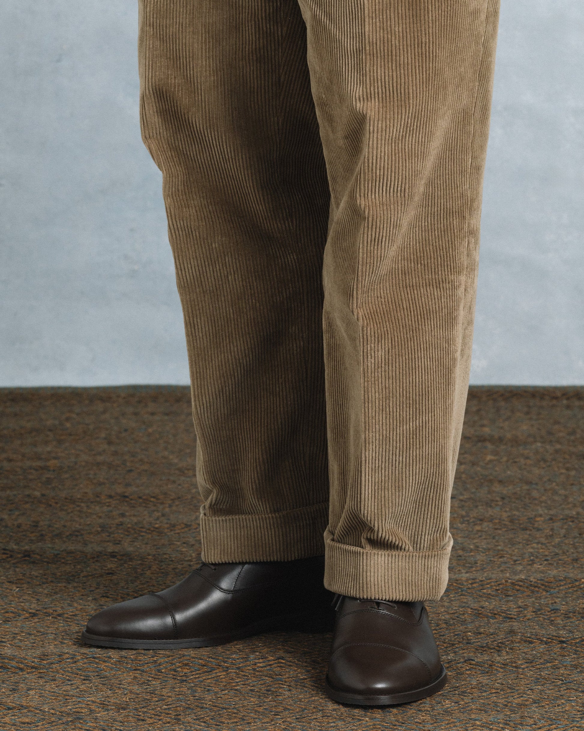 Vinterviken II in dark brown calf, classic oxford shoes with a cap toe design, styled with tan corduroy trousers on a patterned carpet for a refined, versatile look.